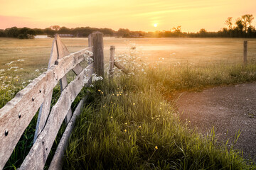 Meadows with wooden fence and rising sun in the early morning