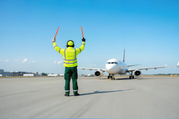 Aviation Marshaller with Signal Wands – Ground Crew Worker Directing Aircraft on Runway for Airline Staff Safety Protocols and Flight Attendant Day Celebrations