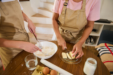 Two Individuals Preparing Dough Together with Ingredients on a Table