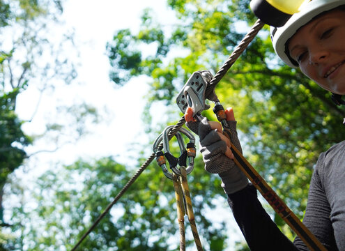 Woman is enjoying an exhilarating ride on a zip line that traverses the thick woods surrounding her