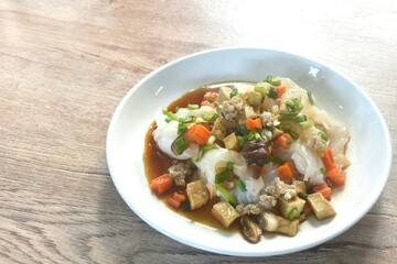 steamed large rice noodles topping chop pork and dice tofu with carrot dressing black soy sauce on plate 