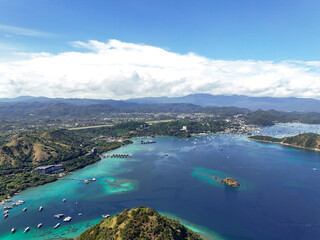 Aerial view of Labuan Bajo from airplane window during landing approach, showing full coastal town,...