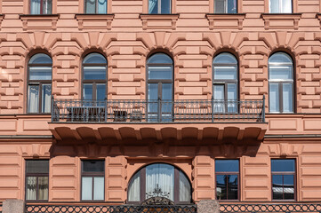 Facade of an ancient building with a iron forged balcony and stucco above the windows.	