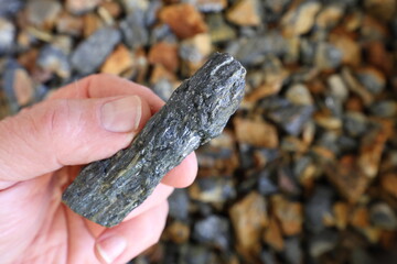 Antimony (Sb) mine, mining. Stibnite ore (antimonite, antimony trisulfide) held in hand. Critical mineral, raw material. Metal used solder, bullets, plain bearings, alloys, lead-acid batteries