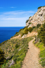 Ppicturesque hiking trail winding through mountains along the stunning coastline of Cyprus. Path offers breathtaking views of turquoise sea, dramatic cliffs. Perfect for adventure, nature lovers.