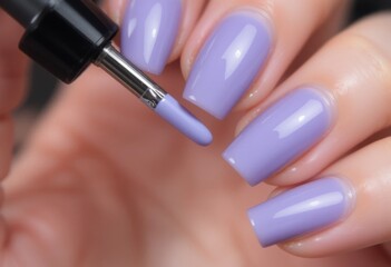 Esmalte en gel aplicado a las uñas con un pincel plano, mostrando un color lavanda brillante y detalles