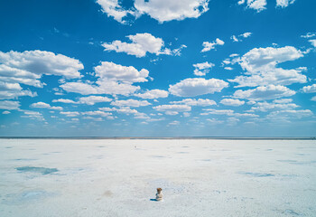 Baskunchak Lake reveals its vast salt flats glistening under the sun, surrounded by a blue sky...