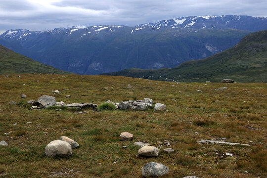 Landscape photo with a view of snowy mountains and large stones in the foreground at sunset on the snowy road Bj&oslash;rgavegen near Aurlandsfjord in Norway