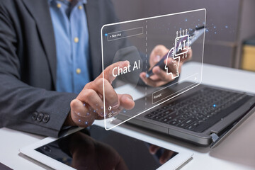 A businessperson interacts with a futuristic AI chatbot interface on a laptop, highlighting advanced artificial intelligence technology in a modern office setting.