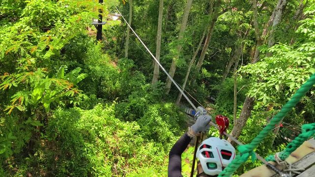 Woman is enjoying an exhilarating ride on a zip line that traverses the thick woods surrounding her