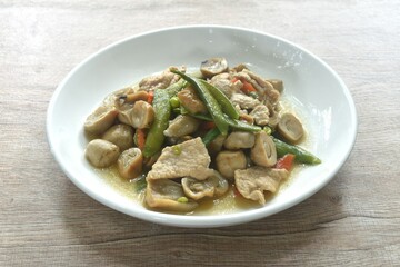 stir fried green pea and straw mushroom with pork in soybean sauce on plate