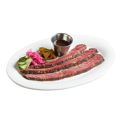 Isolated portion of sliced beef brisket with pickles and sauce