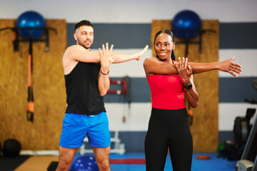 Fitness instructors stretching arms during warm-up exercise in gym