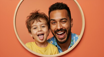 Father and son showing tongues with matching playful expressions in wooden circle frame against coral background. Father's day silly moment celebrating humor and connection