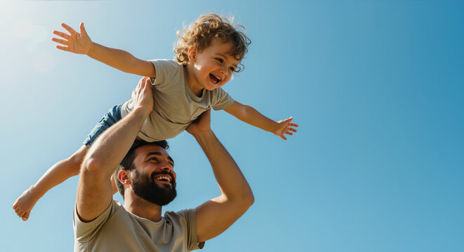 Happy bearded father lifting curly haired toddler son with arms spread against blue sky. Father's day celebration and family bonding activities - Powered by Adobe