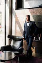 portrait of groom in blue tuxedo in hotel