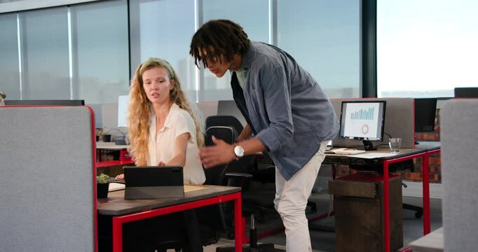 Diverse coworkers seeing chart rise discussing data on tablet before celebrating success at office