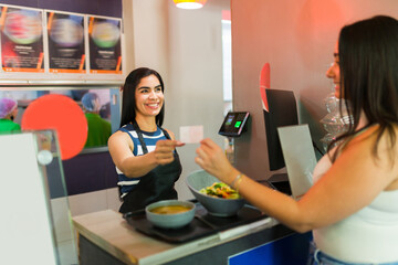Cashier receiving loyalty card from customer in restaurant for salad and soup lunch