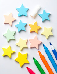Sticky notes shaped like stars scattered across a white table beside colorful highlighters.
