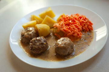 Meatballs with potatoes and carrot salad on a plate