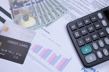 Credit cards, cash, a calculator, and financial documents arranged for financial planning and analysis.