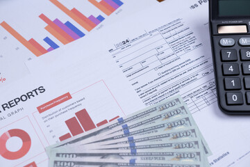 Financial charts, tax documents, a calculator, and US dollar bills represent business analysis and financial planning.