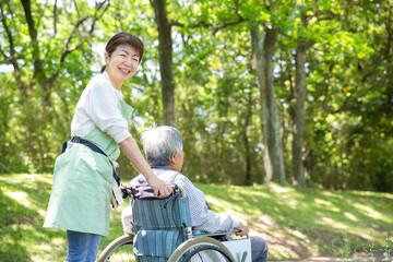 日本人の女性ヘルパー　公園を車椅子の老人と散歩