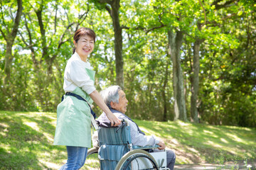 日本人の女性ヘルパー　公園を車椅子の老人と散歩