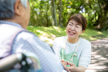 日本人の女性ヘルパー　公園を車椅子の老人と散歩