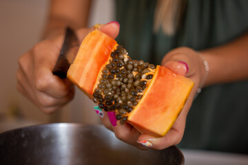 Close up of a woman Woman cutting a Papaya fruit in the kitchen