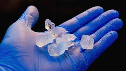A macro view of crystalline flakes resting in a scientist's gloved hand, showcasing intricate textures and details under vivid lighting, emphasizing scientific exploration.