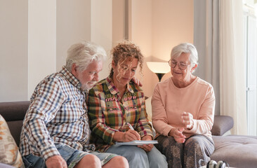 Smiling Senior couple and Caregiver Sharing a Moment sitting together on sofa at home. Concept of...