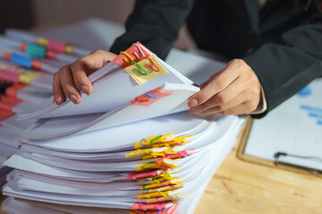 Asian businesswoman working late at night in office under pressure, surrounded by paperwork,...