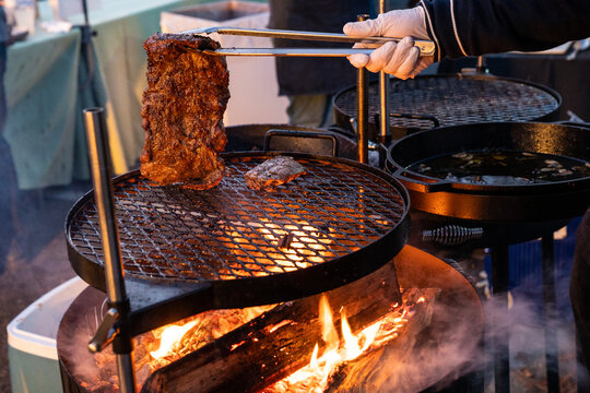 Steak being flipped with cooking on a wood grill 