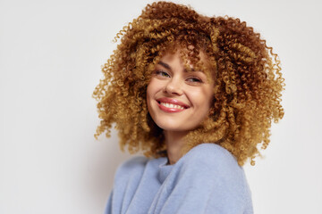 Smiling woman with curly hair against a light background, showcasing vibrant natural curls and a...