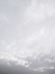 淡いやわらかな空に黒い雲が近づいてきて雨が降りそうな余白が多く文字入れしやすい風景画像。