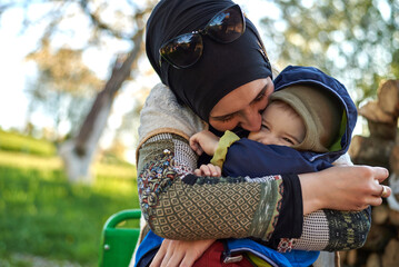A happy Muslim family enjoying the garden. A mother and son kiss and hug with love, smiling and playing together to bond through affection.