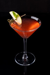 A tantalizing cocktail sits elegantly in a crystal glass, featuring rich ruby hues