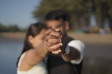 Happy young couple enjoying a romantic moment on a serene beach. The man lifts the woman joyfully while both smile and look relaxed