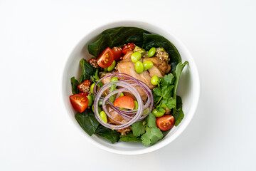 An enticing bowl brimming with nutritious greens, perfectly cooked chicken, and a colorful array of tomatoes, onions, and edamame creates a healthy meal