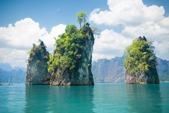 Three rocks Cheo Lan Lake under a bright blue sky and reflected in emerald turquoise waters of the lake in Khao Sok Park. Famous famous nature panoramas and tourist destinations Thailand, Thai nature