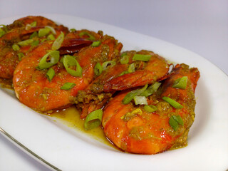Prawn in Padang Sauce, coated in a rich, glossy, reddish-orange savory sauce and brightly garnished with a scattering of freshly chopped green onions, enhancing its visual appeal and aromatic promise