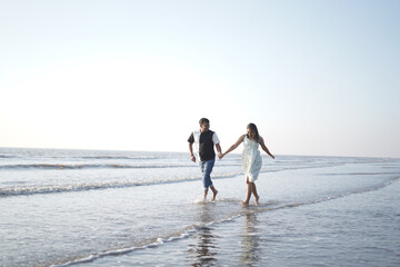Happy young couple enjoying a romantic moment on a serene beach. The man lifts the woman joyfully...