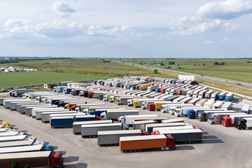 Aerial view of a large truck parking lot at a logistics hub, with multiple commercial semi trucks...