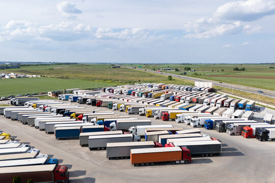 Fototapeta Aerial view of a large truck parking lot at a logistics hub, with multiple commercial semi trucks parked in organized rows.