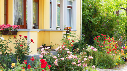 Naklejka premium Sunny yellow house with blooming flowers, warm summer charm