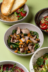 Various bowls filled with colorful salads and dishes showcase an array of fresh vegetables, protein, and herbs. The inviting spread invites shared enjoyment and flavors, perfect for conversation