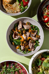 A beautiful array of colorful dishes featuring greens, vibrant vegetables, and tender meats fills a cheerful table