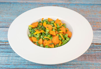 Fresh garden peas and carrots are cooked with salted butter, then garnished with chives and bright marigold flowers for an appealing and colorful side dish.