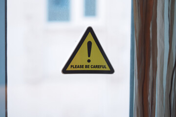 Warning sign urging caution near a window